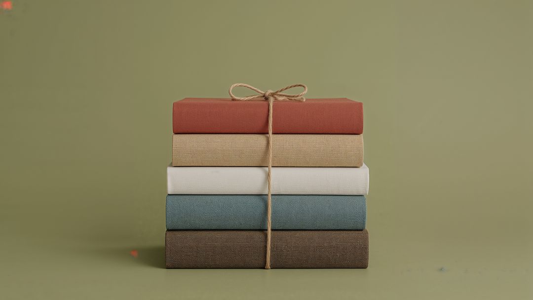 Stack of Hardcover Books Tied with Twine Against Olive Background