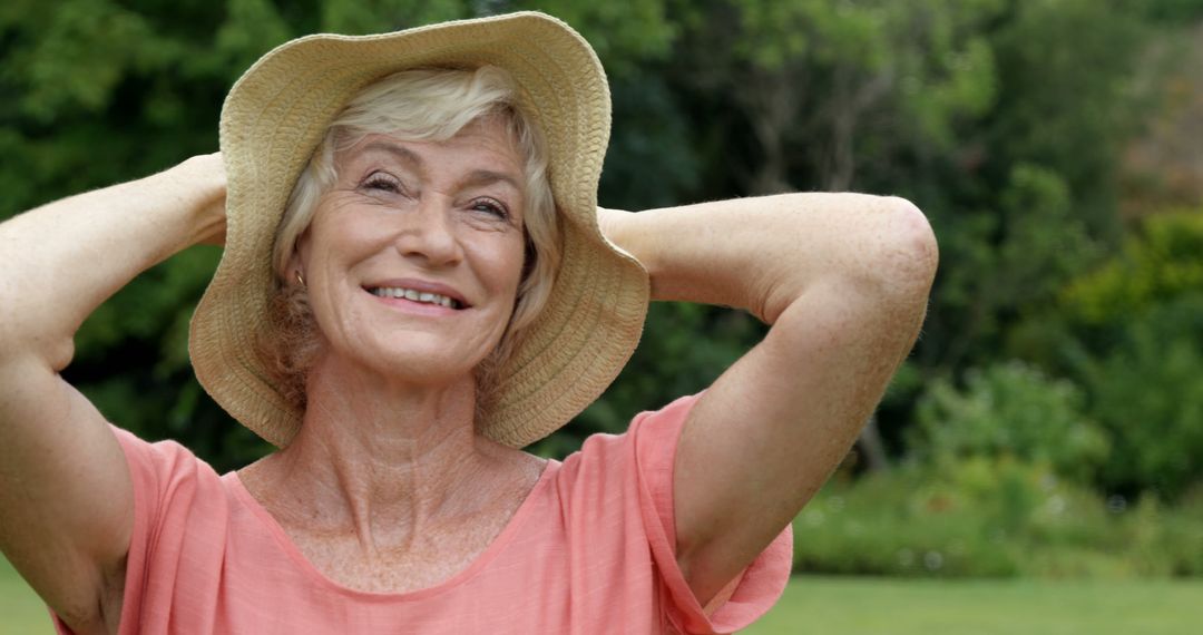 Joyful Senior Woman Enjoys Sunny Day Outdoors Wearing Sun Hat - Free Images, Stock Photos and Pictures on Pikwizard.com