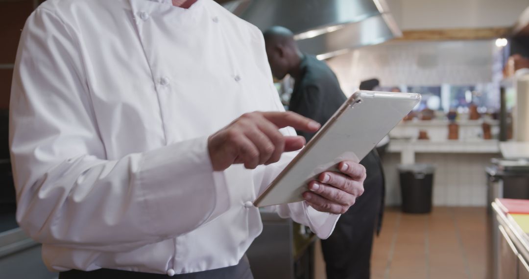 Chef Utilizing Digital Tablet in Busy Commercial Kitchen - Free Images, Stock Photos and Pictures on Pikwizard.com