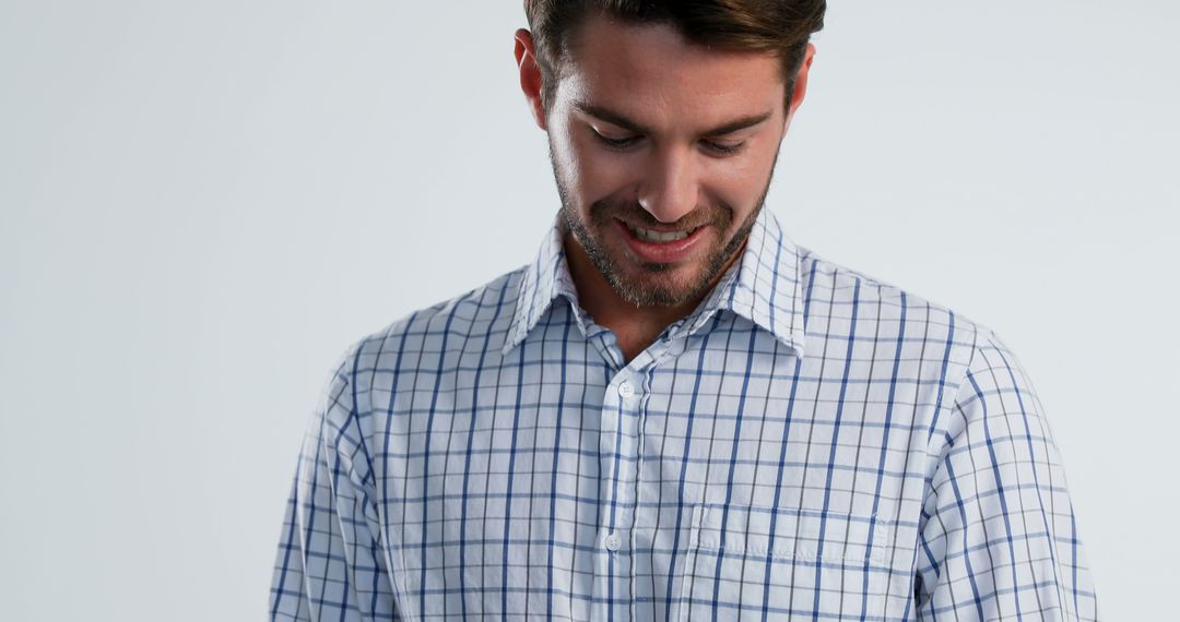 Smiling Man in Checked Shirt Looking Down - Free Images, Stock Photos and Pictures on Pikwizard.com