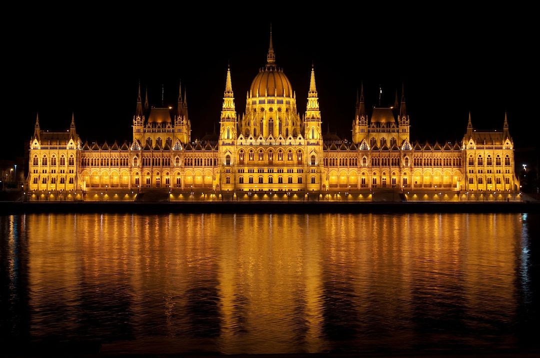Hungarian Parliament Building Illuminated at Night Reflecting in Danube River - Free Images, Stock Photos and Pictures on Pikwizard.com