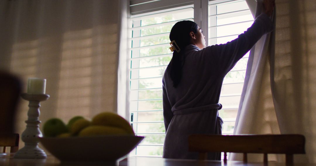 Image of biracial woman opening curtains at home - Free Images, Stock Photos and Pictures on Pikwizard.com