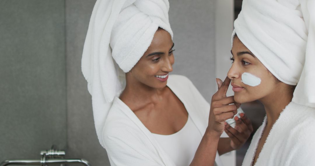 Image of happy diverse female friends in robes moisturizing faces with cream - Free Images, Stock Photos and Pictures on Pikwizard.com