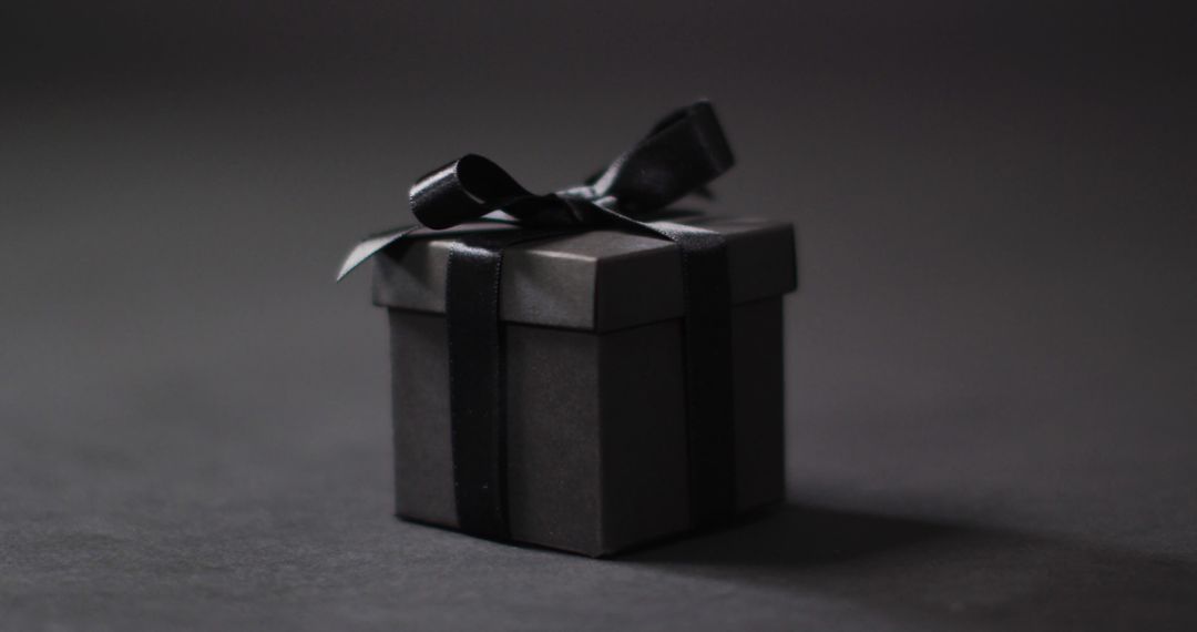 Black gift box with black ribbon on dark grey background with copy space - Free Images, Stock Photos and Pictures on Pikwizard.com