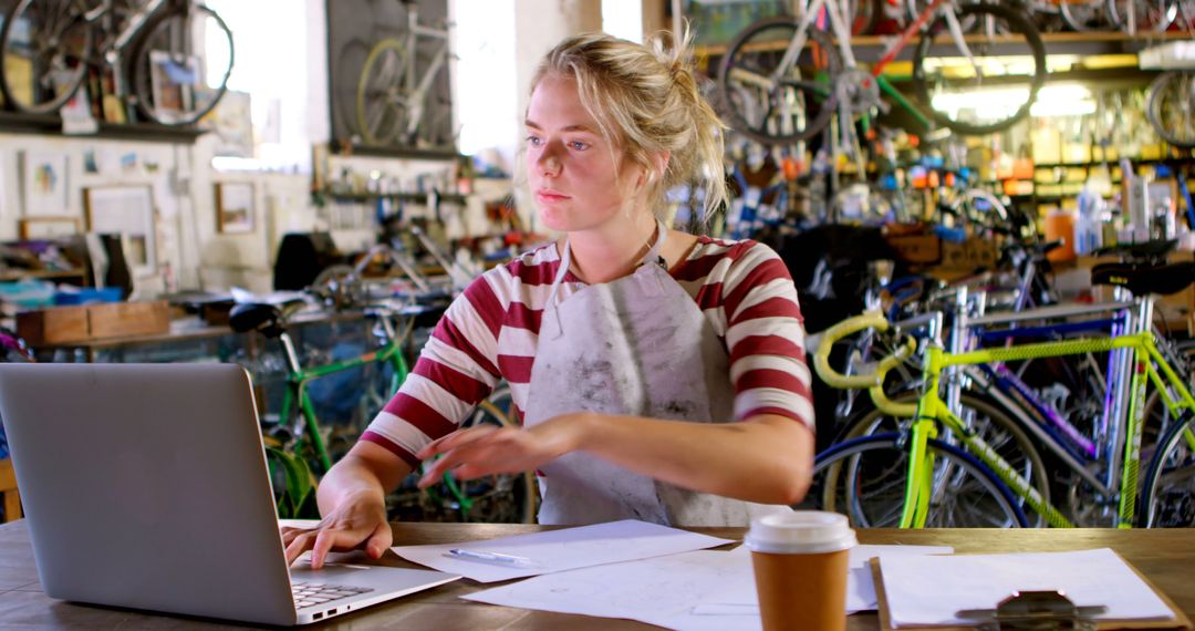 Woman Working on Laptop in Bicycle Workshop - Free Images, Stock Photos and Pictures on Pikwizard.com