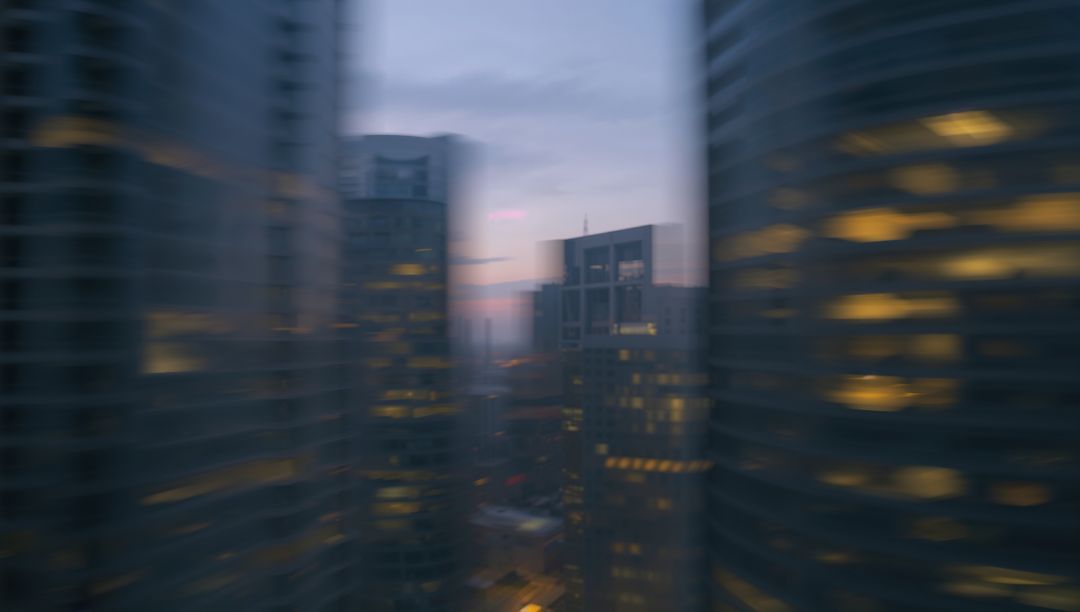 Blurry City Skyscrapers at Dusk Reflecting Urban Glow