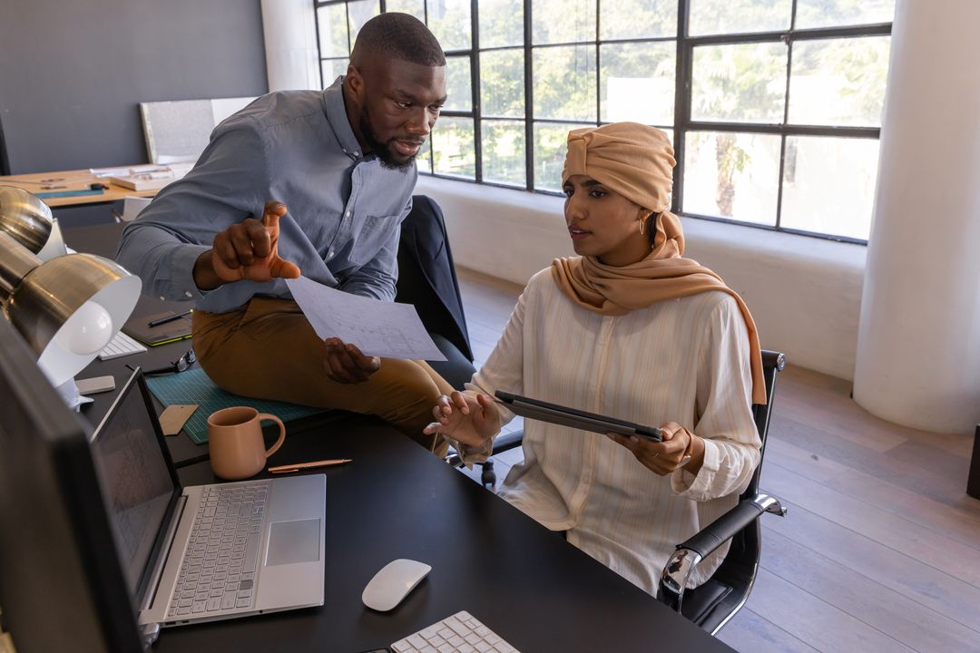 Diverse Coworkers Collaborating in Modern Office with Tablet and Laptop