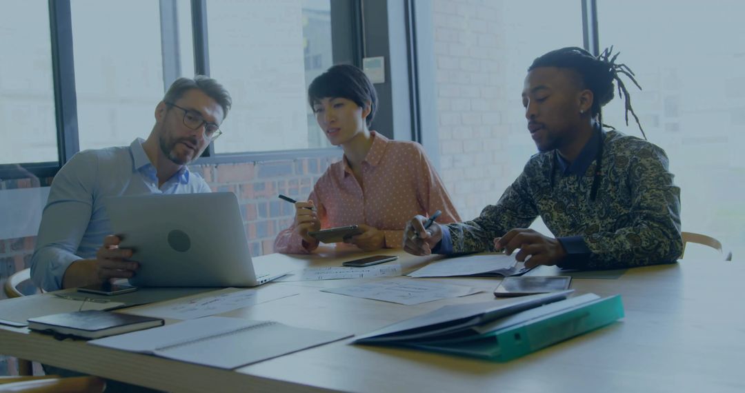 Diverse Professionals Analyzing Reports in Modern Meeting Room