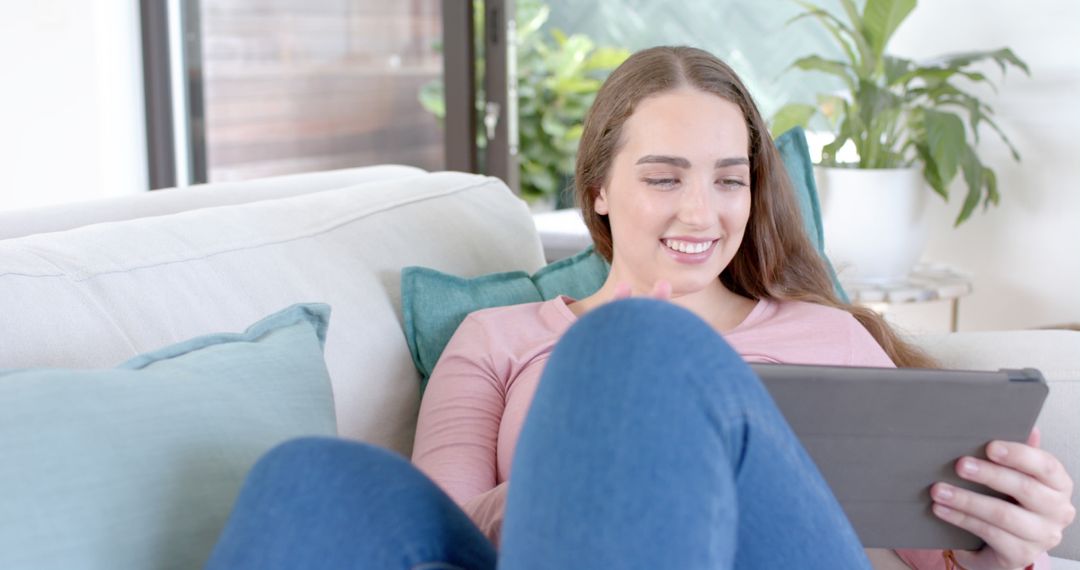 Young Woman Relaxing on Sofa and Using Tablet - Free Images, Stock Photos and Pictures on Pikwizard.com