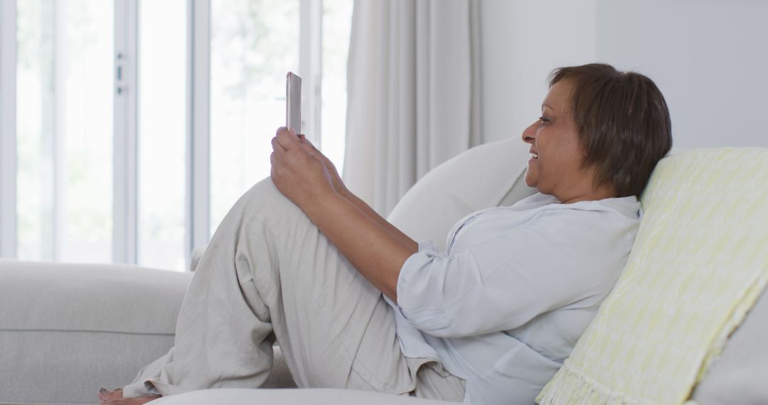 Older Woman Relaxing on Couch Using Tablet - Free Images, Stock Photos and Pictures on Pikwizard.com