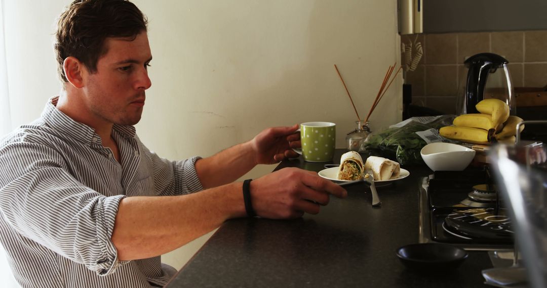 Man Having Breakfast with Wrap and Coffee at Kitchen Counter - Free Images, Stock Photos and Pictures on Pikwizard.com