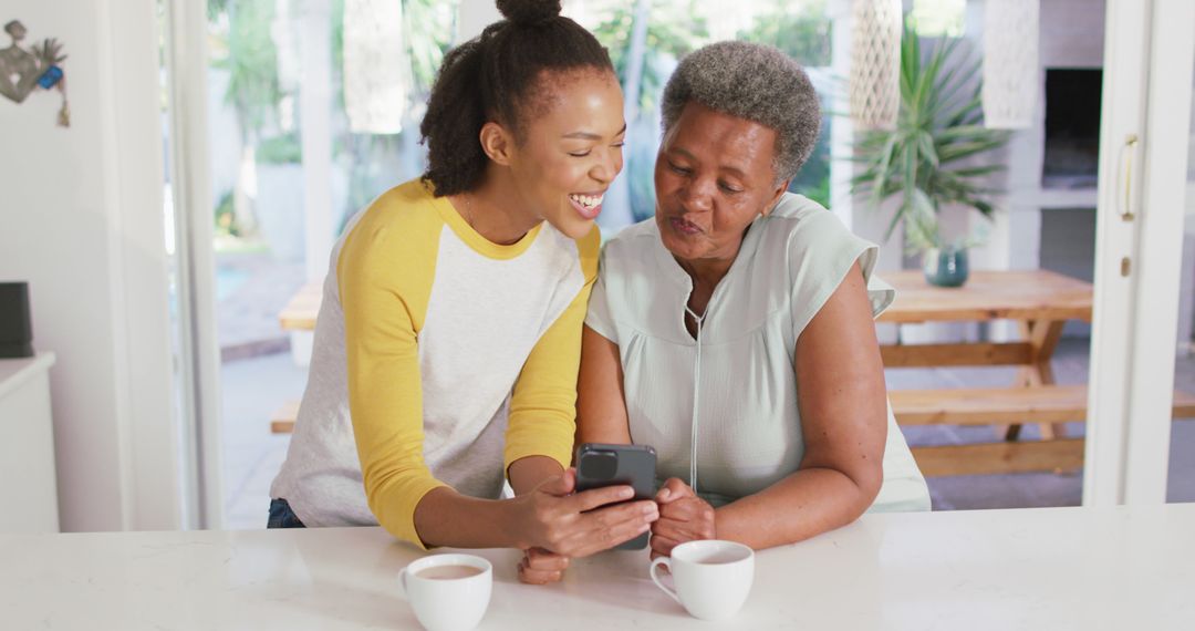 Happy Mother and Daughter Enjoying Quality Time at Home With Smartphone