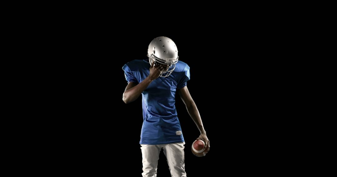 Teen American Football Player Reflecting Holding Ball - Free Images, Stock Photos and Pictures on Pikwizard.com