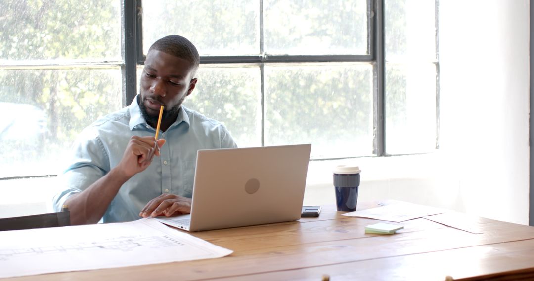 Focused Professional Reviewing Blueprints at Office Desk