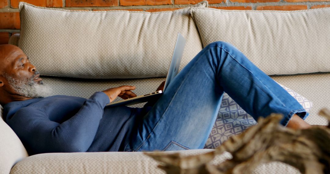 Middle-aged Man Relaxing on Sofa Using Laptop at Home - Free Images, Stock Photos and Pictures on Pikwizard.com