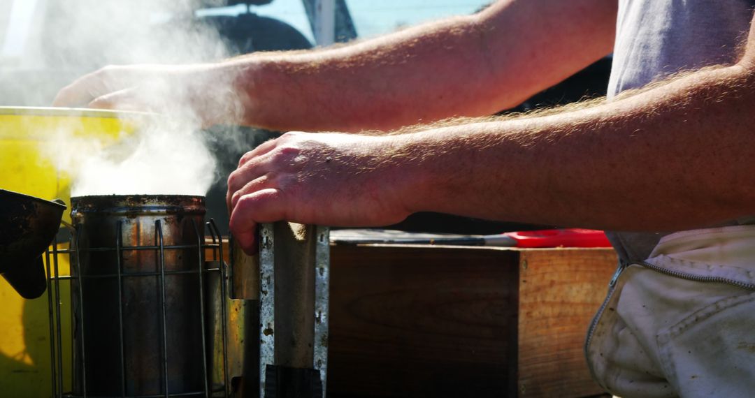 Beekeeper Handling Smoker Equipment with Steam Outdoors - Free Images, Stock Photos and Pictures on Pikwizard.com