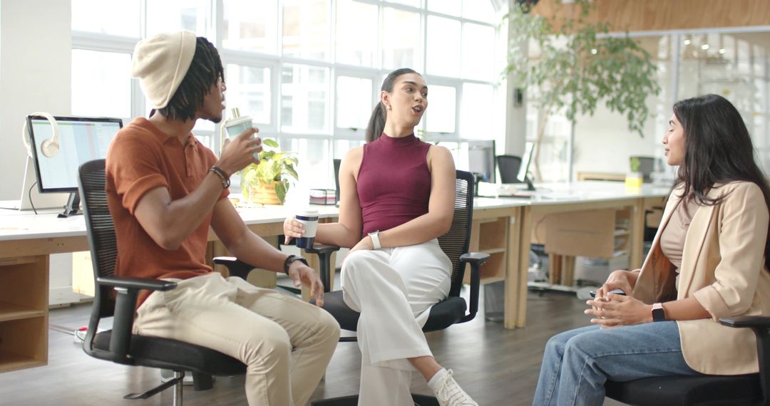 Multicultural team collaborating over coffee in bright modern open office with greenery
