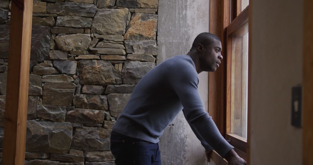 Man Looking Out Window in Rustic Home Interior