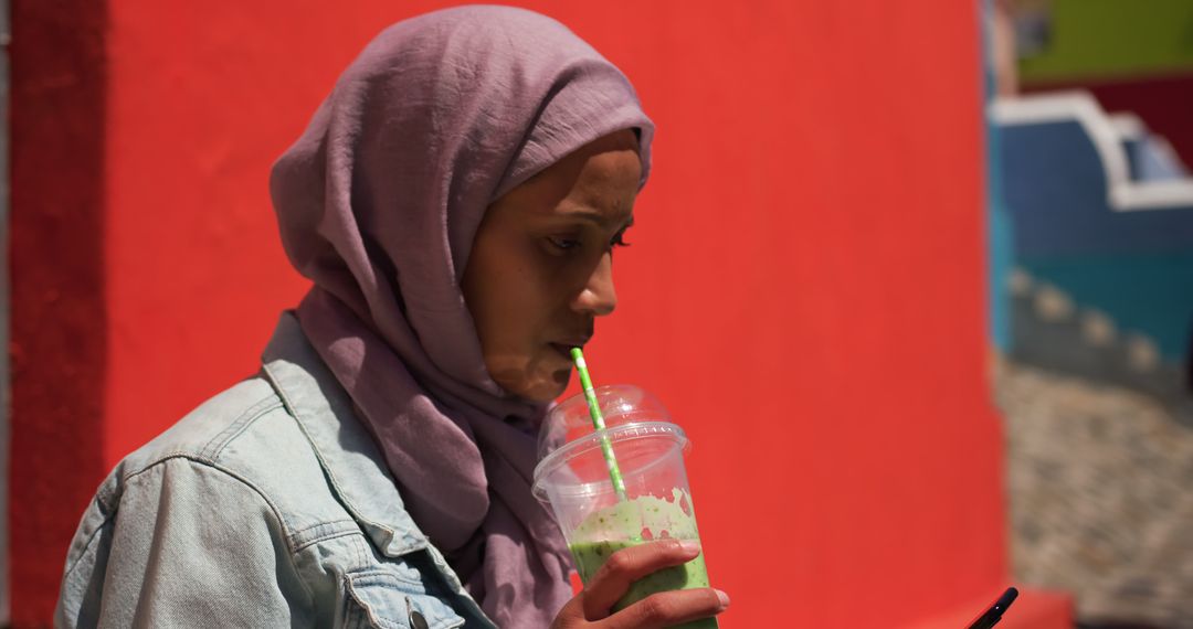 Young Woman in Hijab Drinking Matcha Drink and Using Smartphone - Free Images, Stock Photos and Pictures on Pikwizard.com