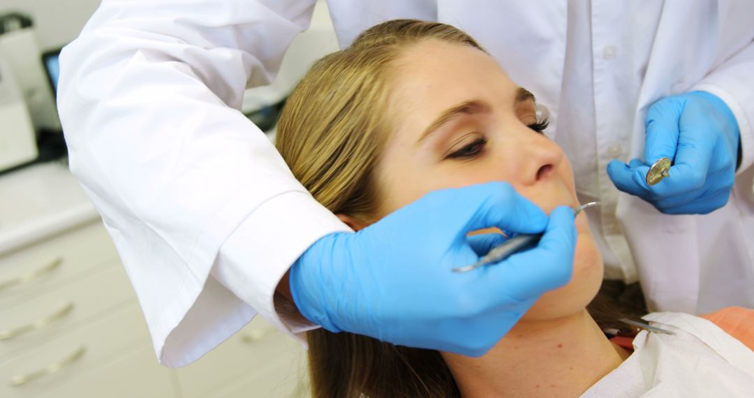 Dentist Treating Female Patient With Blue Gloves in Dental Clinic - Free Images, Stock Photos and Pictures on Pikwizard.com