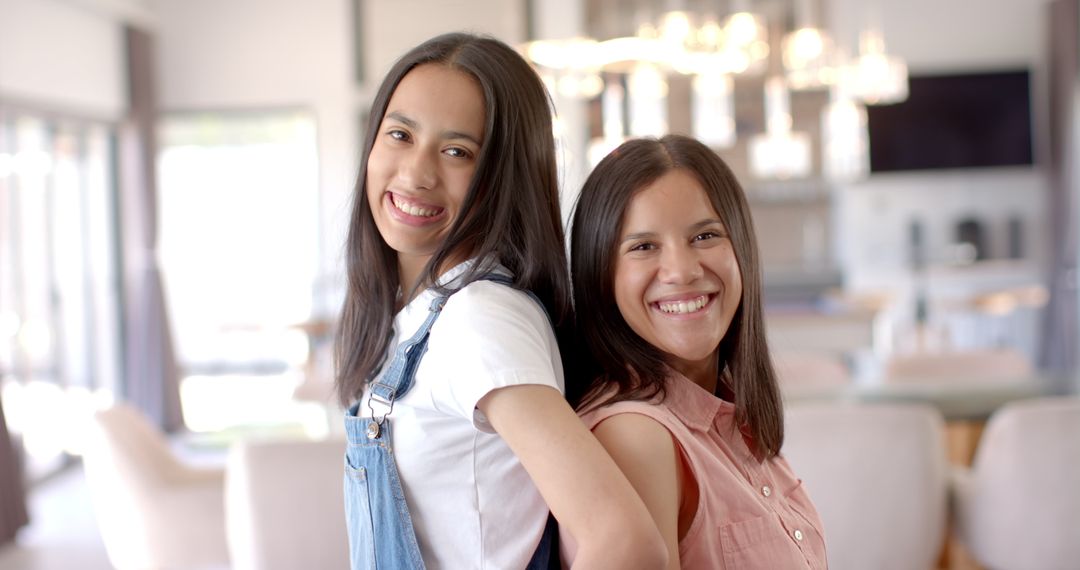 Smiling Two Girls Standing Back to Back in Bright Home