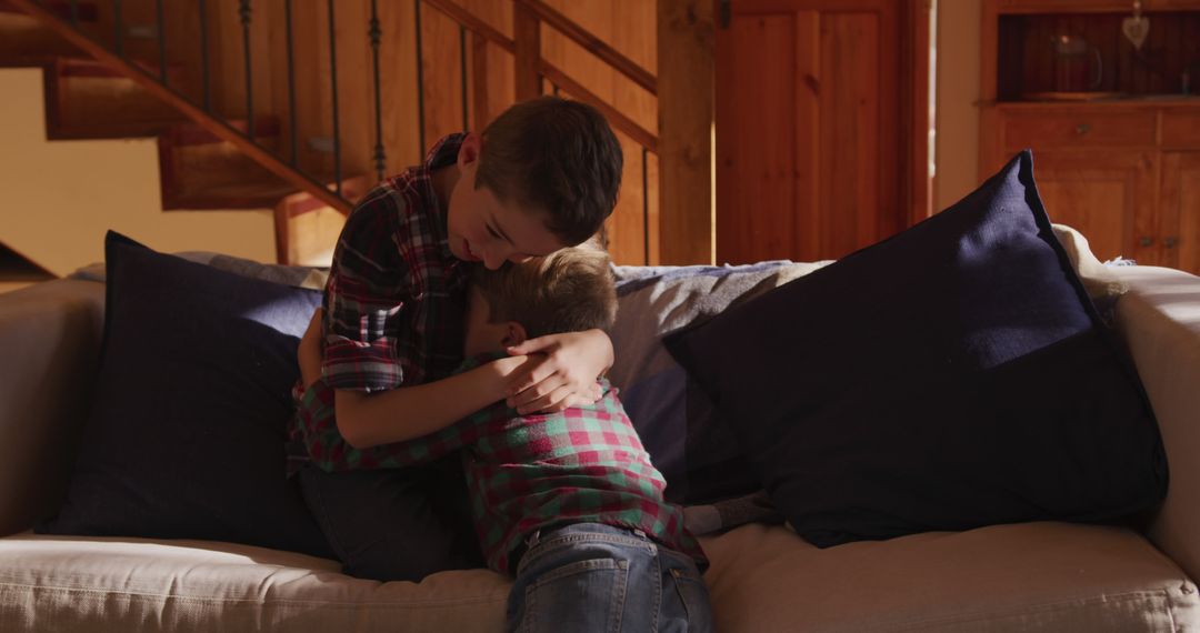 Two Young Boys Hugging on Cozy Couch in Warmly Lit Living Room - Free Images, Stock Photos and Pictures on Pikwizard.com