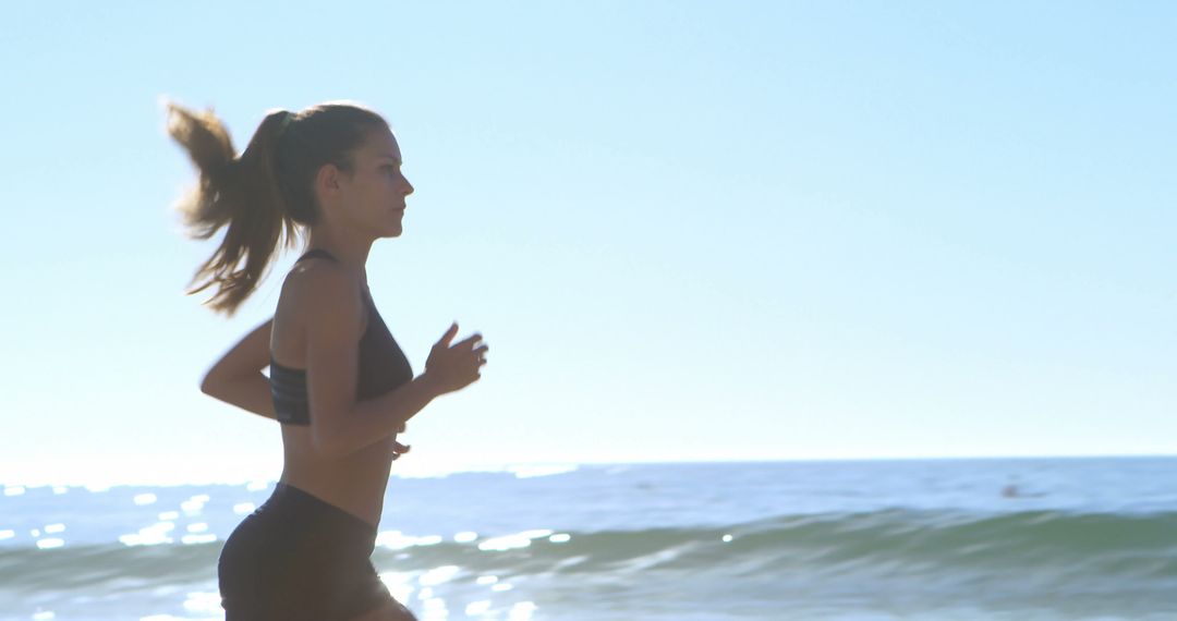 Young woman running at beach during sunny day - Free Images, Stock Photos and Pictures on Pikwizard.com