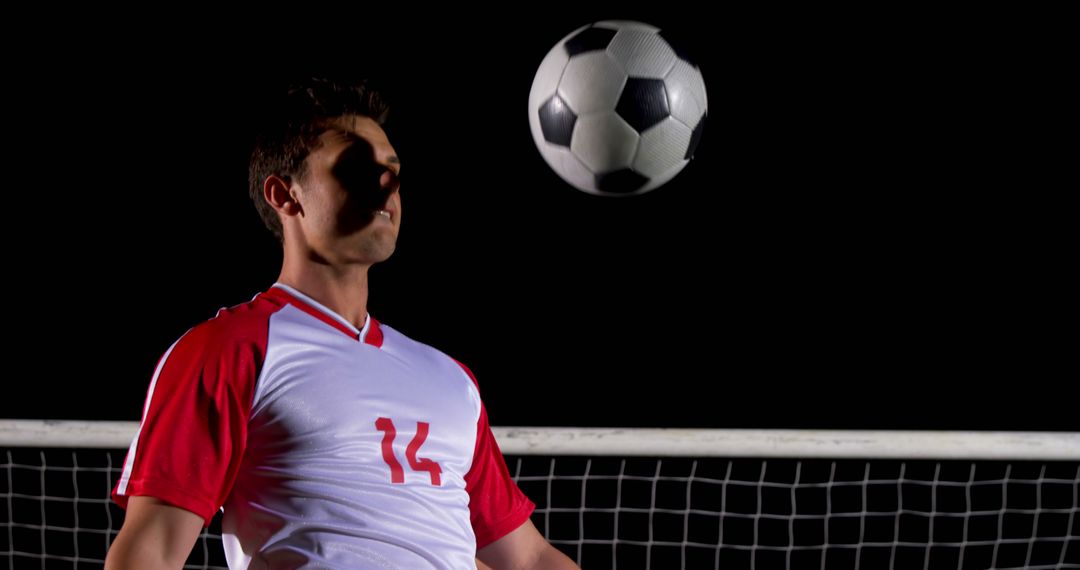 Soccer Player Heading Ball During Game at Night - Free Images, Stock Photos and Pictures on Pikwizard.com