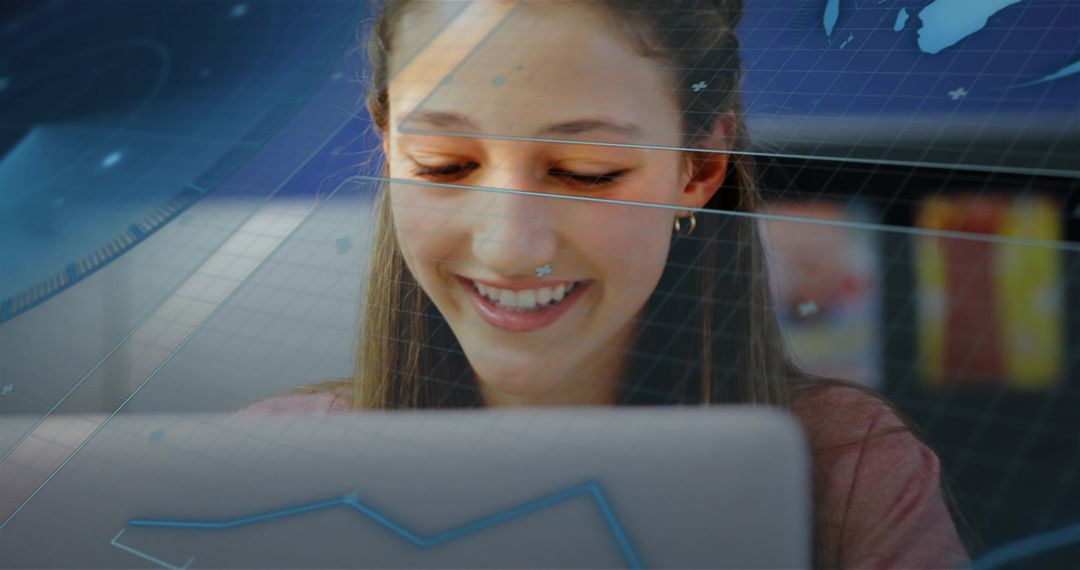 Smiling teenage student studying on laptop with digital data overlays in coworking cafe