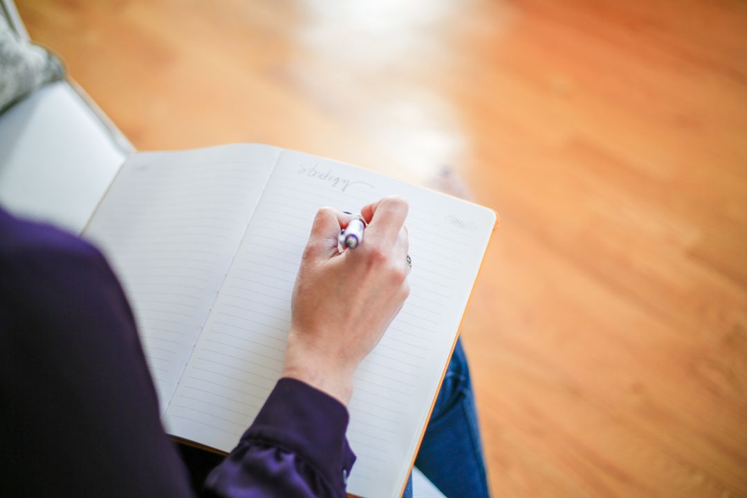 Woman Writing in Notebook on Wooden Floor