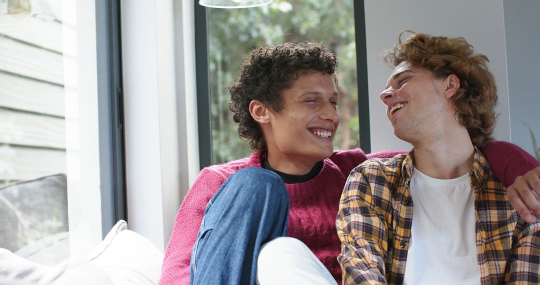 Two Young Men Smiling and Relaxing Together on Couch - Free Images, Stock Photos and Pictures on Pikwizard.com