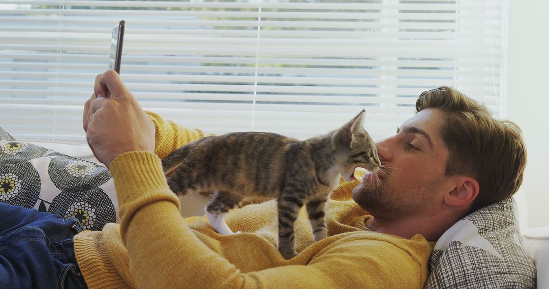 Young Man Relaxing on Couch with Playful Kitten