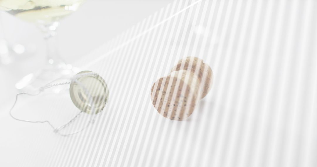 Speckled champagne corks resting on white tabletop with muselet wire and cap, minimalist