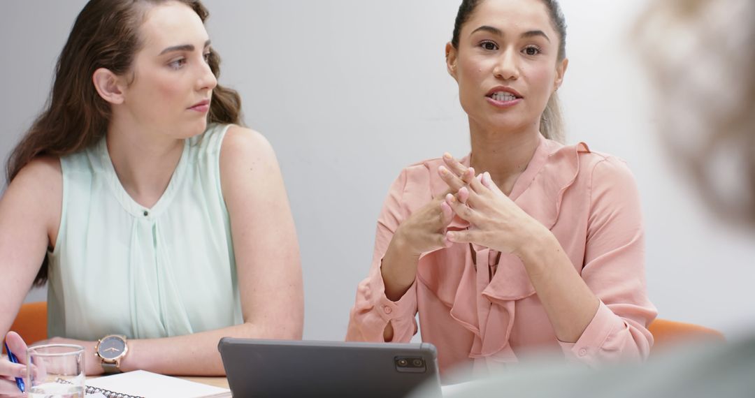 Diverse Women Engaged in Office Meeting with Tablet