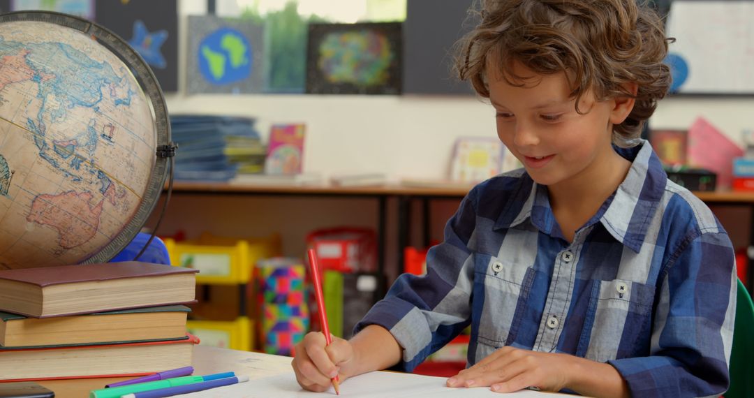 Engaged Schoolboy Writing at Desk in Classroom Environment