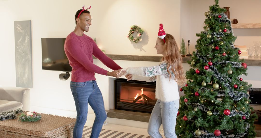 Joyful Couple Dancing at Home Near Christmas Tree and Fireplace