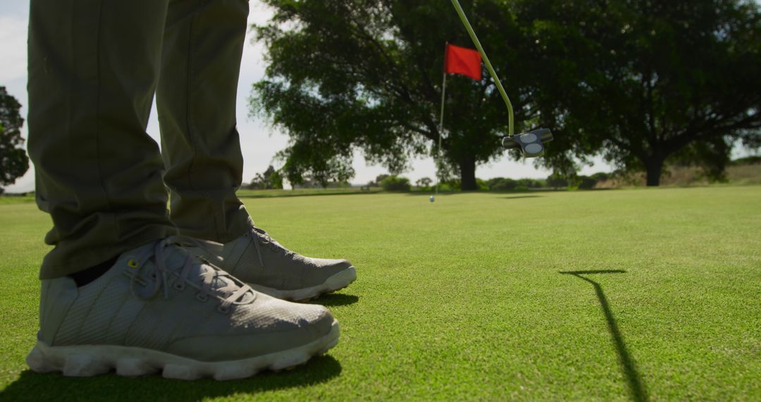 Golfer Preparing to Putt on Green with Red Flag in Background - Free Images, Stock Photos and Pictures on Pikwizard.com