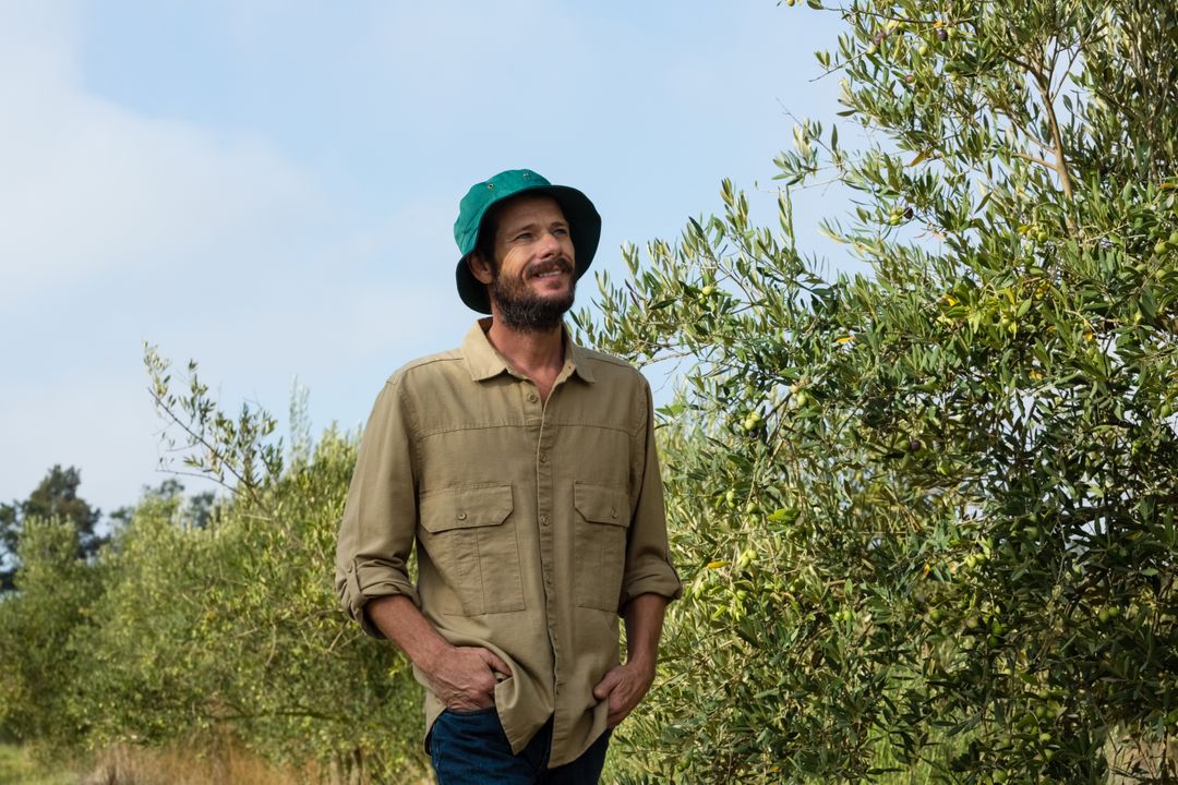 Smiling Farmer Standing in Olive Grove - Free Images, Stock Photos and Pictures on Pikwizard.com