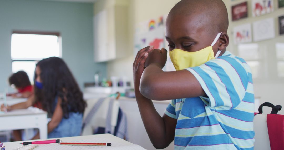 Young Student Sneezing into Elbow in Classroom Wearing Face Mask - Free Images, Stock Photos and Pictures on Pikwizard.com