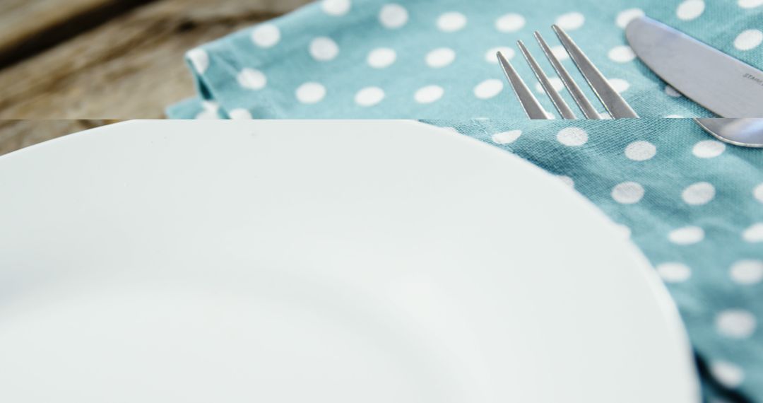 A white plate paired with a fork and knife rests on a polka-dotted napkin, with copy space - Free Images, Stock Photos and Pictures on Pikwizard.com