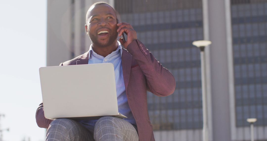 Smiling Professional Conversing on Smartphone While Using Laptop Outdoors