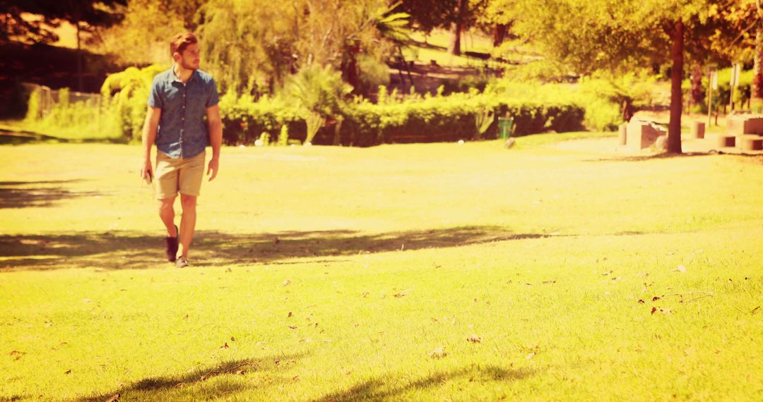 Young Man Walking Outdoors on Sunny Day in Park - Free Images, Stock Photos and Pictures on Pikwizard.com