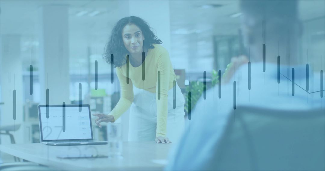 Confident woman presenting analytics dashboard pointing at laptop in open office meeting