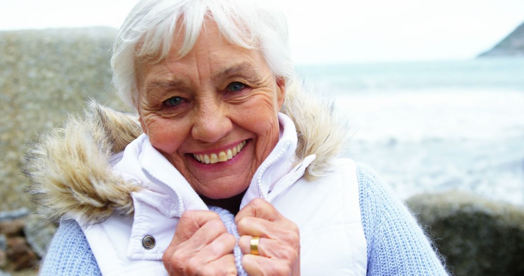 Smiling Senior Woman on Beach in Winter Clothing - Free Images, Stock Photos and Pictures on Pikwizard.com