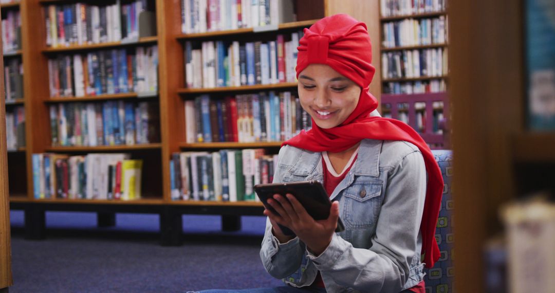 Smiling Teen Girl in Red Hijab Using Tablet in Library - Free Images, Stock Photos and Pictures on Pikwizard.com