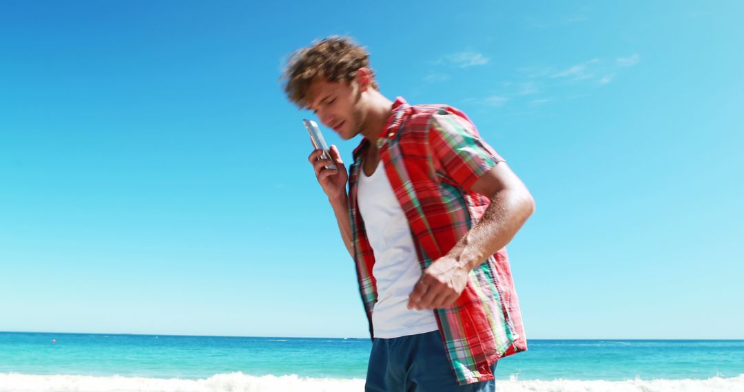 Young Man with Curly Hair Talking on Phone at Sunny Beach - Free Images, Stock Photos and Pictures on Pikwizard.com