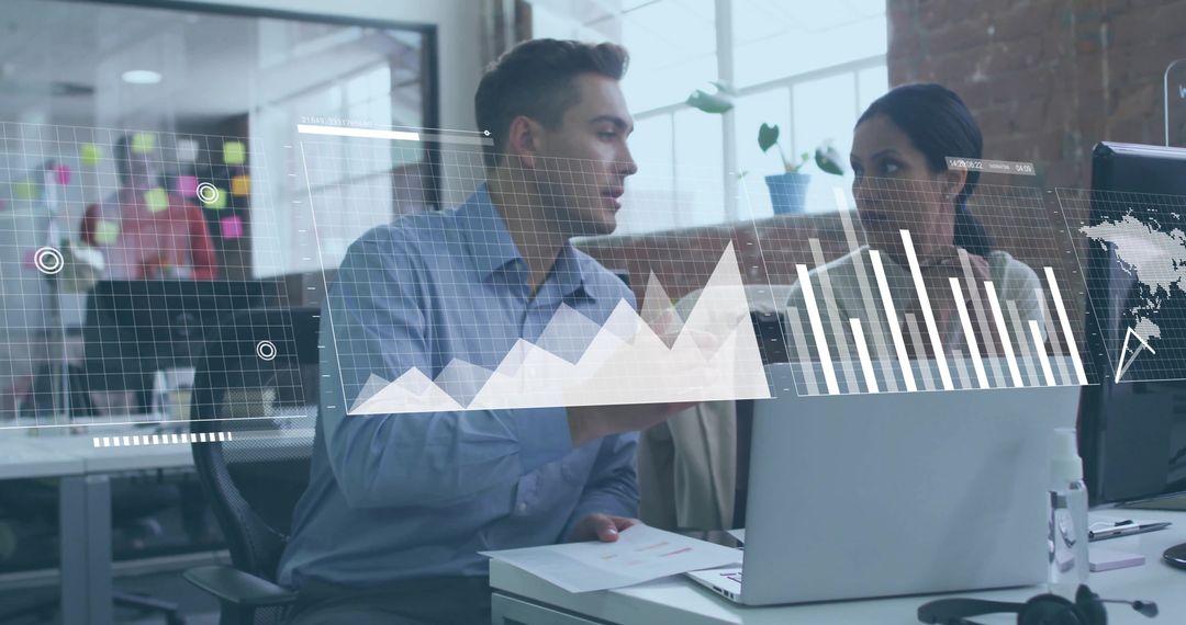Colleagues analyzing digital charts on laptop in modern open-plan office