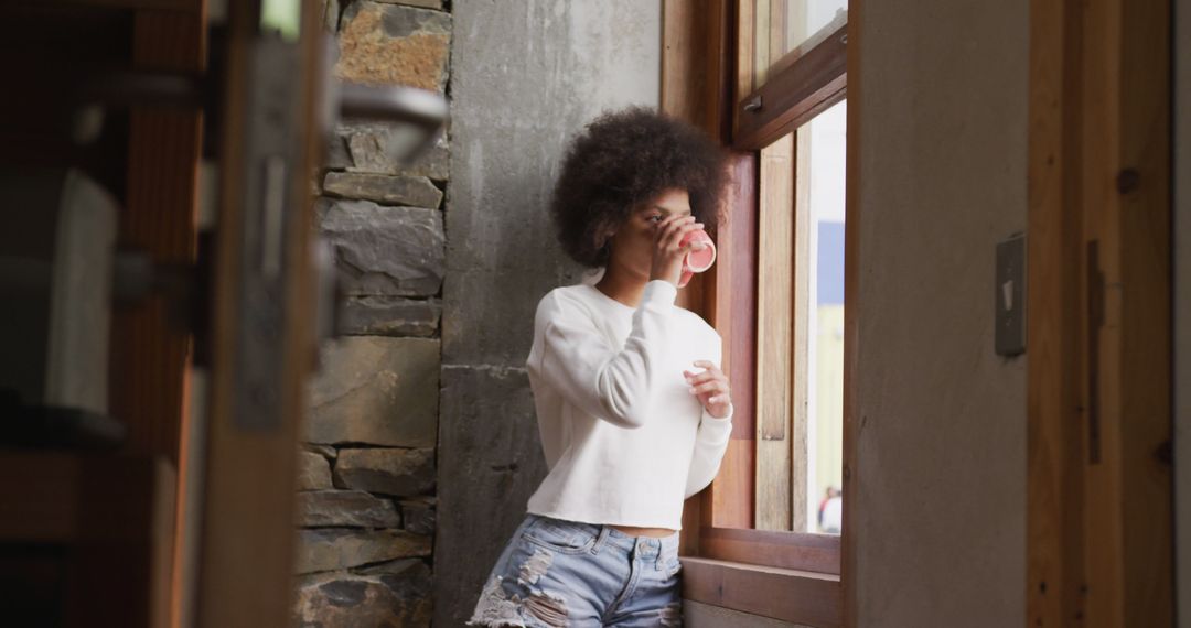 Young Woman Drinking Coffee by Window in Rustic Home - Free Images, Stock Photos and Pictures on Pikwizard.com