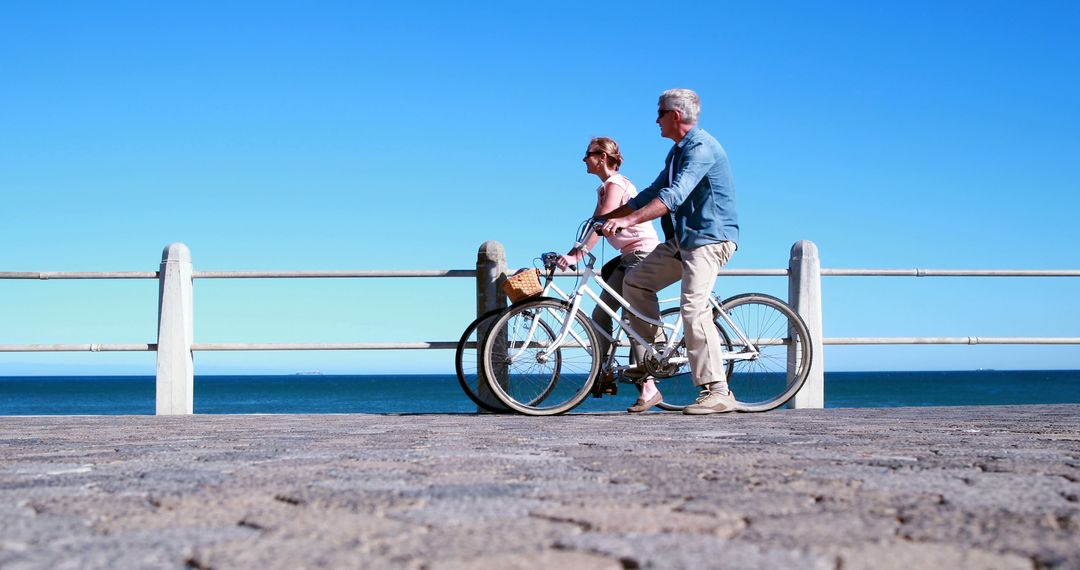 Senior Couple Riding Bicycles Along Seaside Promenade on Sunny Day - Free Images, Stock Photos and Pictures on Pikwizard.com