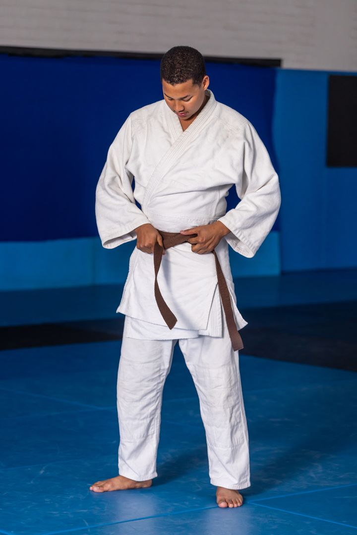 Martial Artist Focused on Tying Brown Belt in Dojo